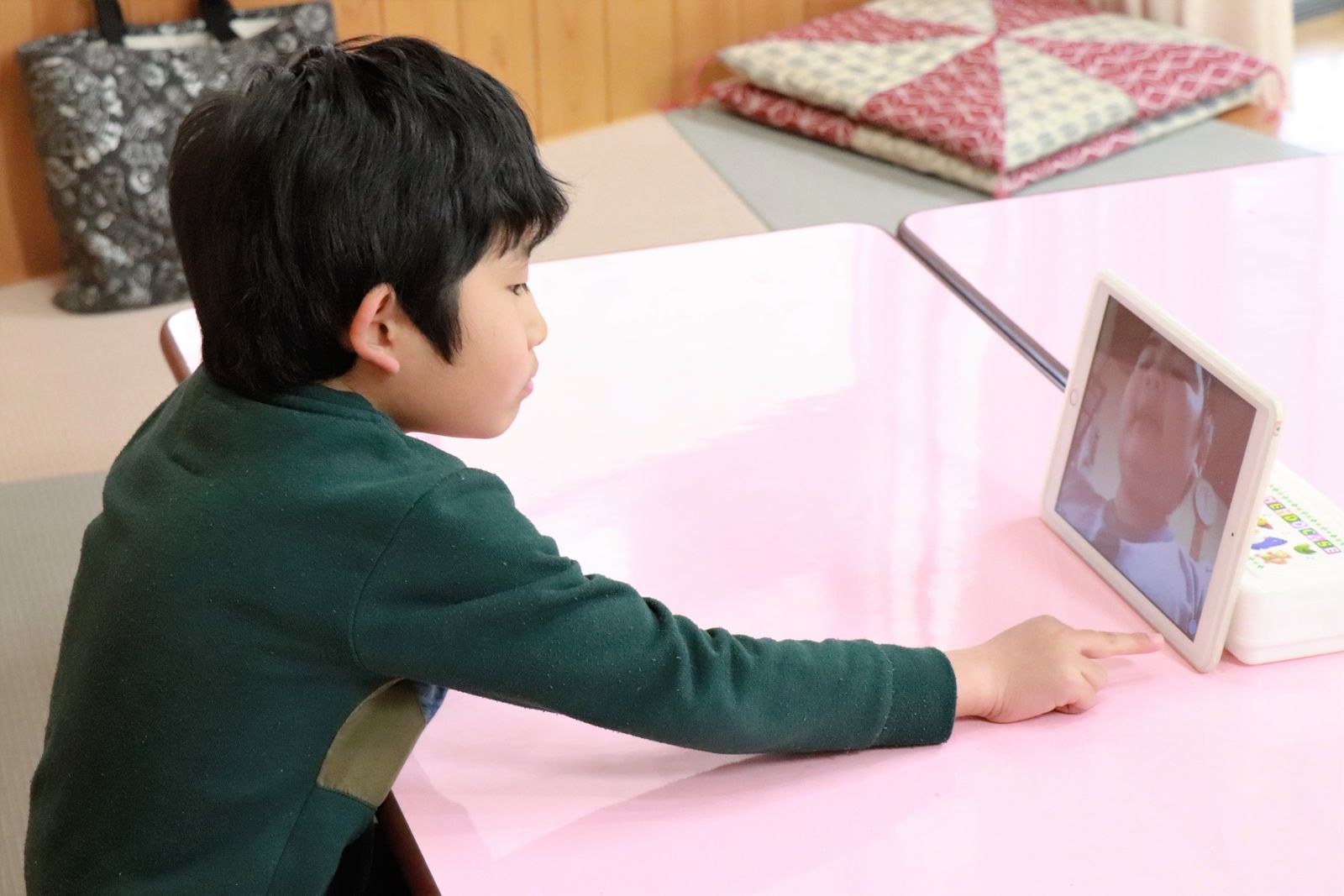 タブレットの画面を見て学ぶ子ども